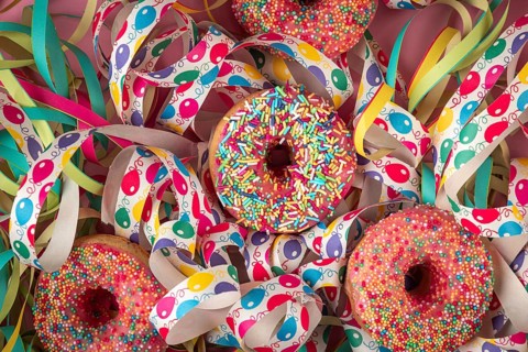 Colourful donuts nestled in colorful streamers that create a festive atmosphere, carnival