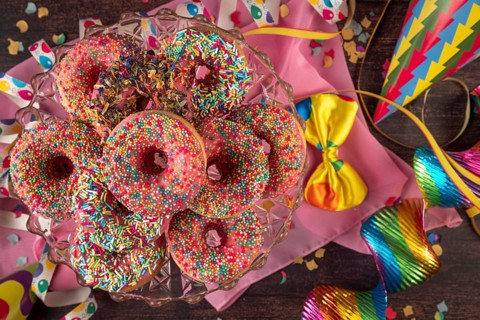 Colourful donuts with party decorations such as streamers, bow and confetti, carnival