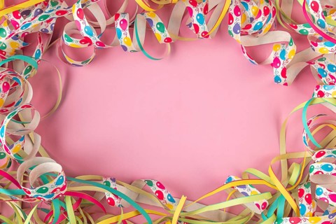 Colourful streamers form a frame on a pink background, Mardi Gras