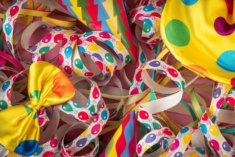 Colourful streamers with party hats and a yellow bow on a cheerful background, Mardi Gras
