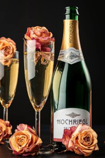 Champagne glasses with rose petals and bottle, festive atmosphere, dark background
