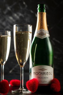 Champagne bottle and filled glasses with red heart decorations, on dark background
