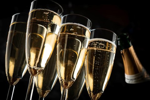 Several champagne glasses and a bottle against a dark background