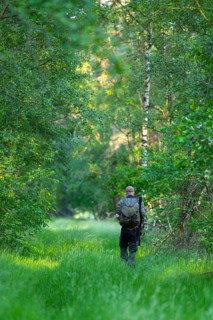 Hunter with backpack and gun goes to the residence, Ahlhorn, Lower Saxony, Germany