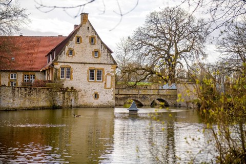 An old moated castle in Melle Haus Sondermühlen with bridge, surrounded by a large pond and trees