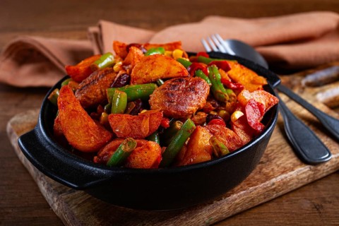 Steakhouse pfanne, fried potato slices, with meatballs, and vegetable mixture, on a black plate