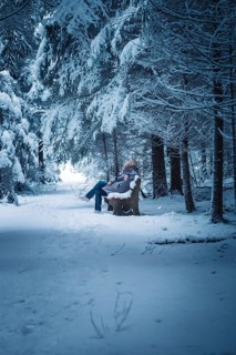 A person sitting on a bench in a snowy forest, Broomfield, Black Forest, Germany