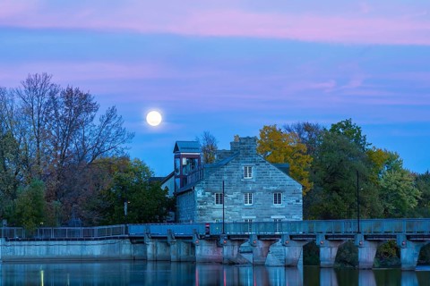 Illuminated Moulin Neuf water flow control dam and walkway over Des Mille-Iles river plus New Mill