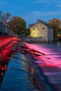 Illuminated Moulin Neuf water flow control dam and walkway over Des Mille-Iles river plus New Mill