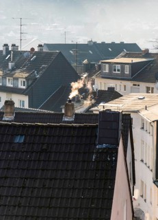 Smoke plume from a chimney over densely built residential area in the evening light, wintry city