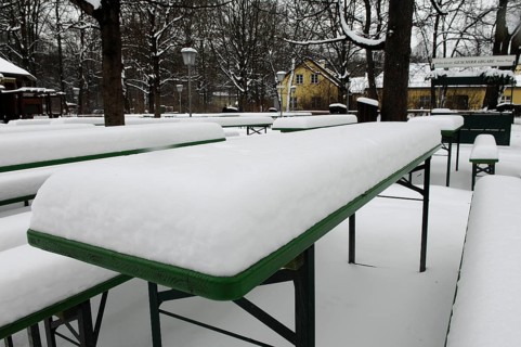 Winter in the English Garden, snow-covered beer garden tables and benches, Munich, Bavaria, Germany