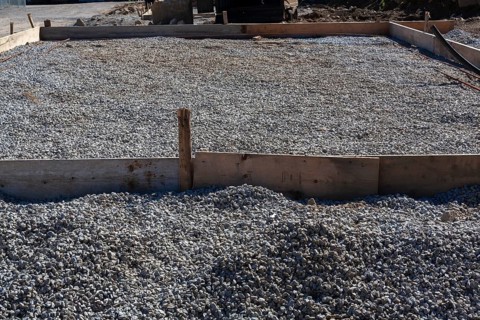 Wooden concrete pouring forms and bed of crushed and compacted stone aggregate to rest concrete