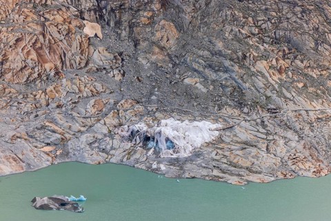 Remains of the Rhone Glacier ice cave covered with protective white geotextile sheets, highlighting