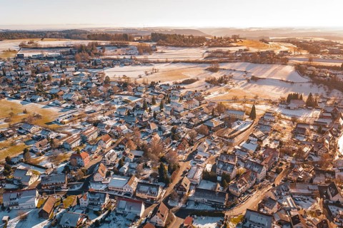 Aerial view of a snowy village with adjacent fields in the soft light of a winter sunset,