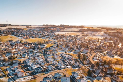 Bird's-eye view of rural winter landscape with snow-covered houses and fields, Hallwangen,