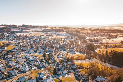 A wintry hilly landscape with a village under snow-covered roofs, surrounded by fields, Hallwangen,