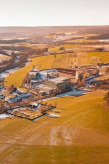 Wintery field landscape with industrial buildings in the distance under clear skies, Hallwangen,