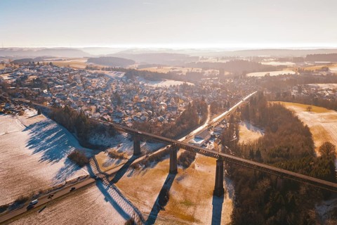 Snowy landscape with bridge and wide view of a village in warm light, Aach, Dornstetten,