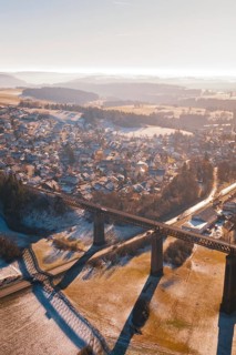 Aerial view of a snowy village and bridge with a wide view over the countryside, Aach, Dornstetten,