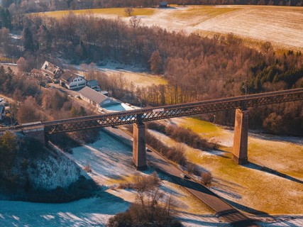 Bridge spanning a snowy valley next to a village under mild sunlight, Aach, Dornstetten,