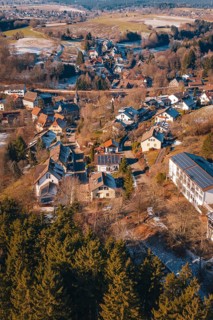 Aerial view of a snowy village with numerous roofs and surrounding forest, Aach, Dornstetten,