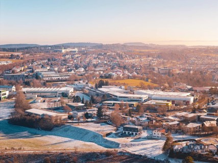 City view in winter with snow-covered fields and buildings under a foggy sky, Dornstetten,