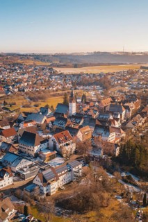 Aerial view of a town with church in the center, surrounded by buildings and winter landscape under