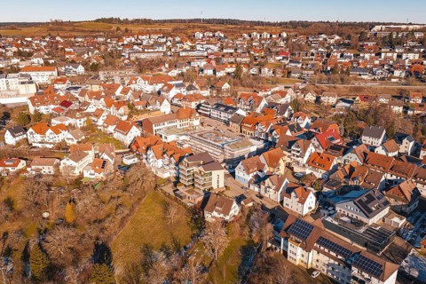 Aerial view of a city with many buildings and red roofs, in a wintry landscape in sunshine,
