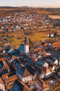 Aerial view focusing on church surrounded by city buildings in a wintry environment in sunlight,