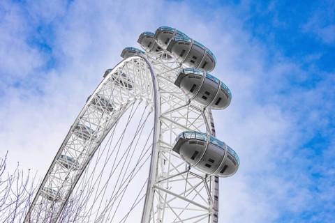 View of a Ferris wheel with white cabins against a blue sky, London Eye, London, United Kingdom