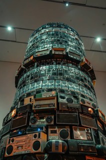 Tower-like installation of stacked radios in a brightly lit room, Tate Modern of Art, Lodon, United
