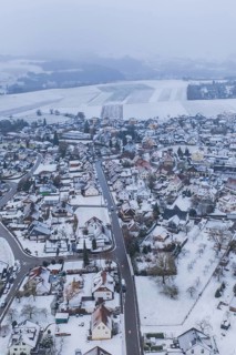 Snowy city landscape with houses and fields under a grey sky, Empfingen, Freudenstadt district,
