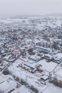 Aerial view of a snowy village with houses, roads and surrounding fields, Empfingen, Freudenstadt