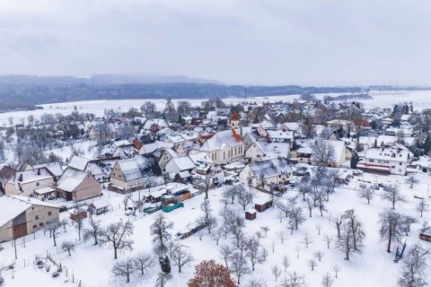 Snowy village with church in the center, surrounded by winter landscape, Wiesenstetten,