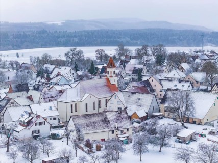 Snowy village landscape in winter, dominating church surrounded by trees, Wiesenstetten,