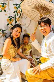 Young family with toddler and parasol in traditional clothing present themselves for the