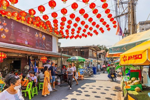 Busy access road covered with red lanterns, to Wat Arun Buddhist temple, Bangkok, metropolis of