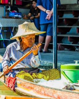 Old woman with her wooden boat on the Damneon Saduak floating markets channel, near Bangkok,