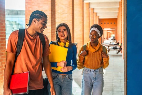 Diverse students walking, carrying books and backpacks, communicating happily while moving through