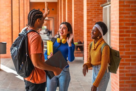 Group of diverse university students on campus, one male and two females, standing in a brick