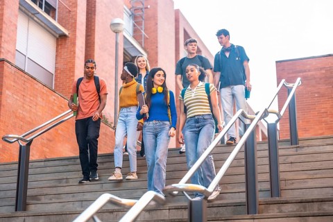 Group of diverse university students walking down outdoor stairs on campus, carrying backpacks and