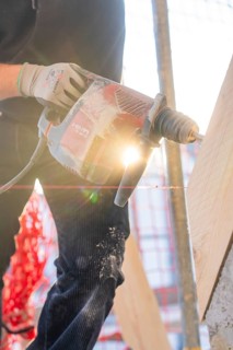 Drilling work in sunlight on construction site with wooden elements, carpentry construction, roof
