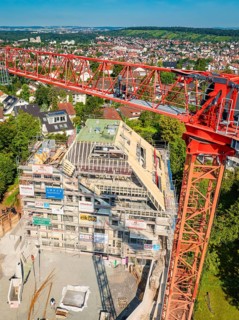 Crane rising high above a construction site with urban landscape in the background, construction