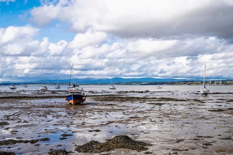 Boats on mud of Forth Estuary over Blackness Castle, Blackness, Scotland, UK