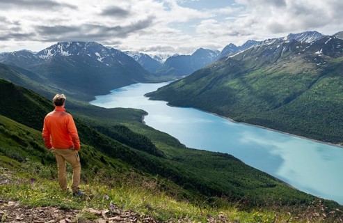 Mountaineer enjoys views of blue lake and mountains on Twin Peaks Trail, Eklutna Lake, Chugach
