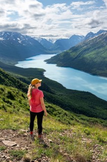 Female mountaineer enjoying views of blue lake and mountains on Twin Peaks Trail, Eklutna Lake,