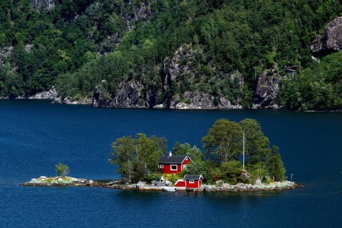 Small island in Lovrafjord with a red house surrounded by blue waters, Lovrafjord, Ryfylke, Norway