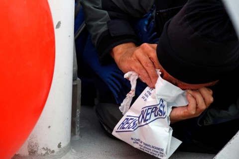 Person uses a vomit bag during a whale watching trip, Andenes, Vesterålen, Norway
