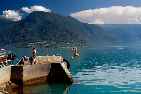 Summer jump into cool water from a jetty in the fjord, Solvorn, Norway