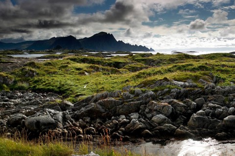 Rugged coastal area with green grassy areas and dramatic skies in Andenes, Vesterålen, Norway